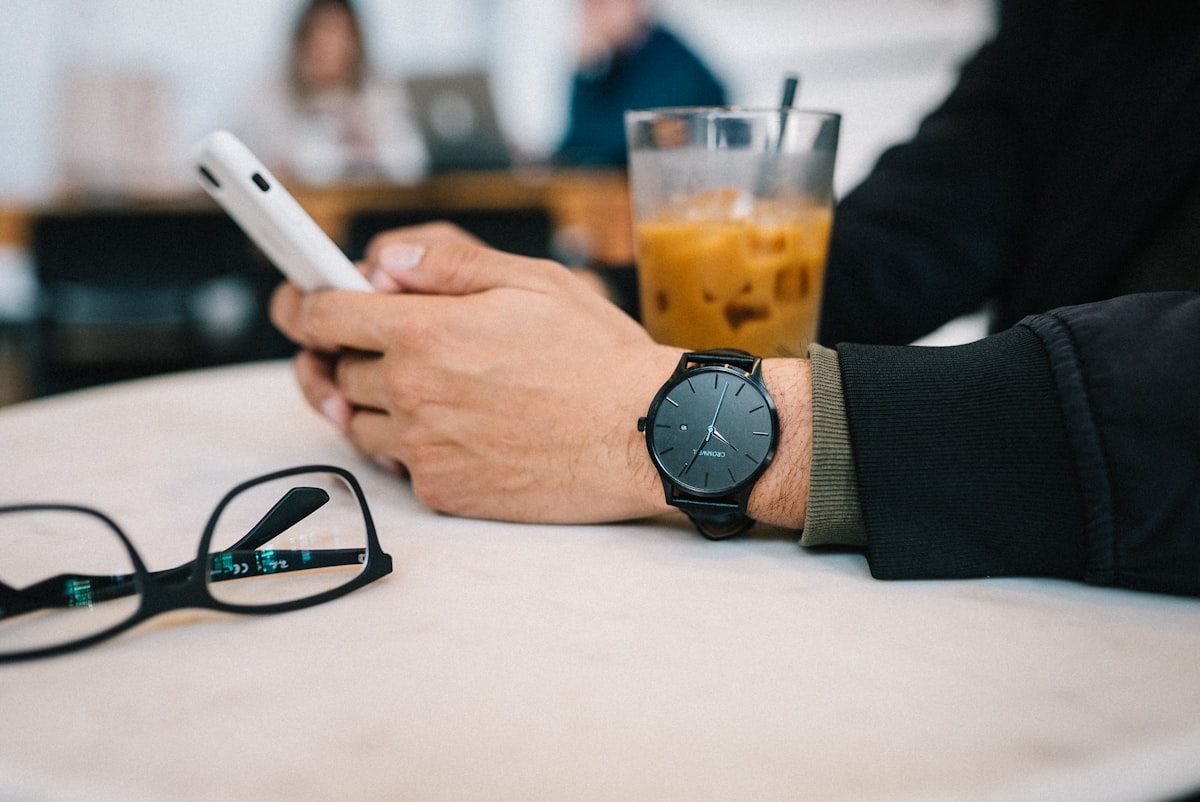 Mão segura o celular em uma mesa de café, respondendo uma conversa