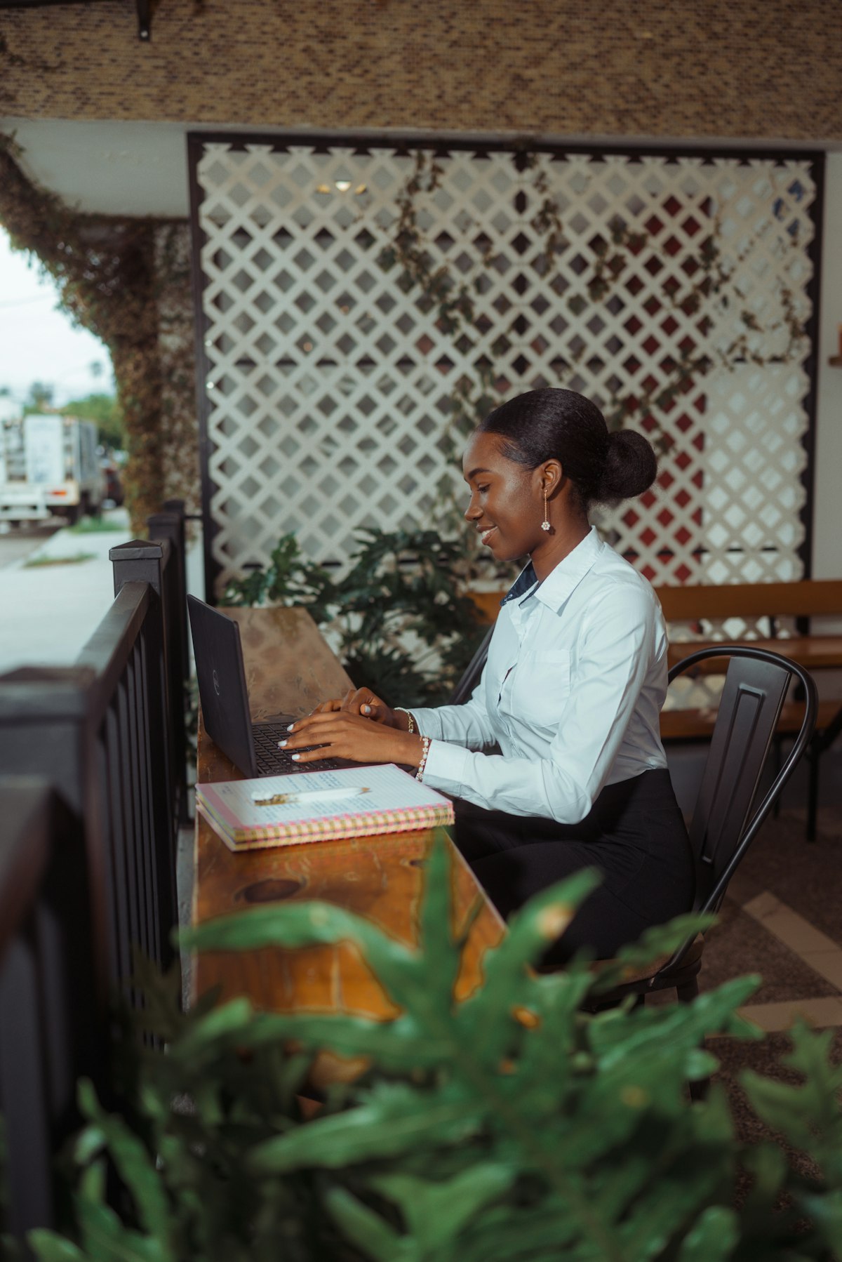 Profissional trabalhando no notebook em um espaço com plantas, de perfil